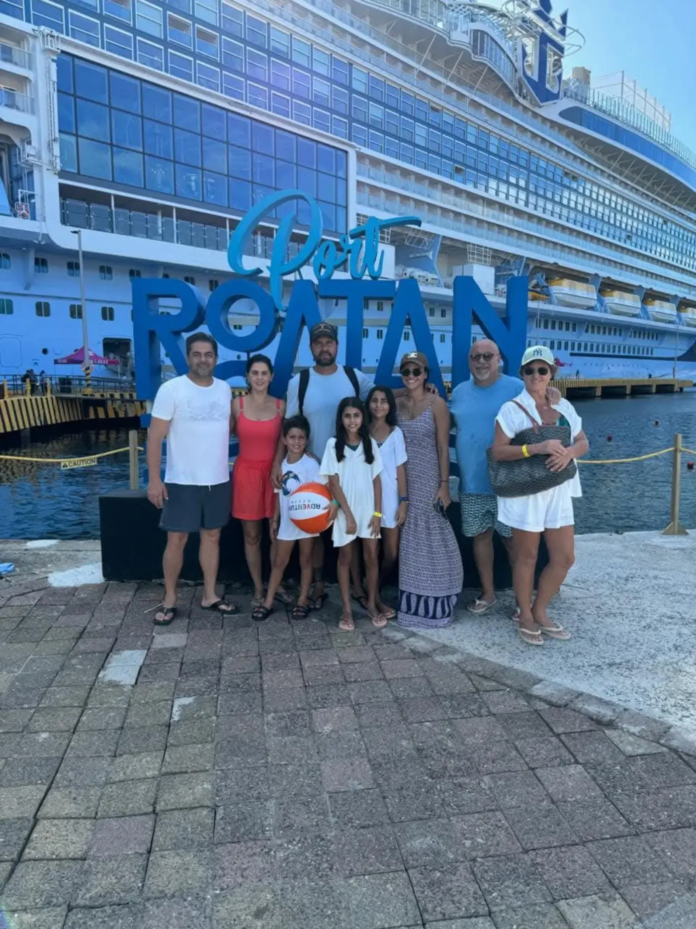 Family group tour at Roatán cruise port with docked ship